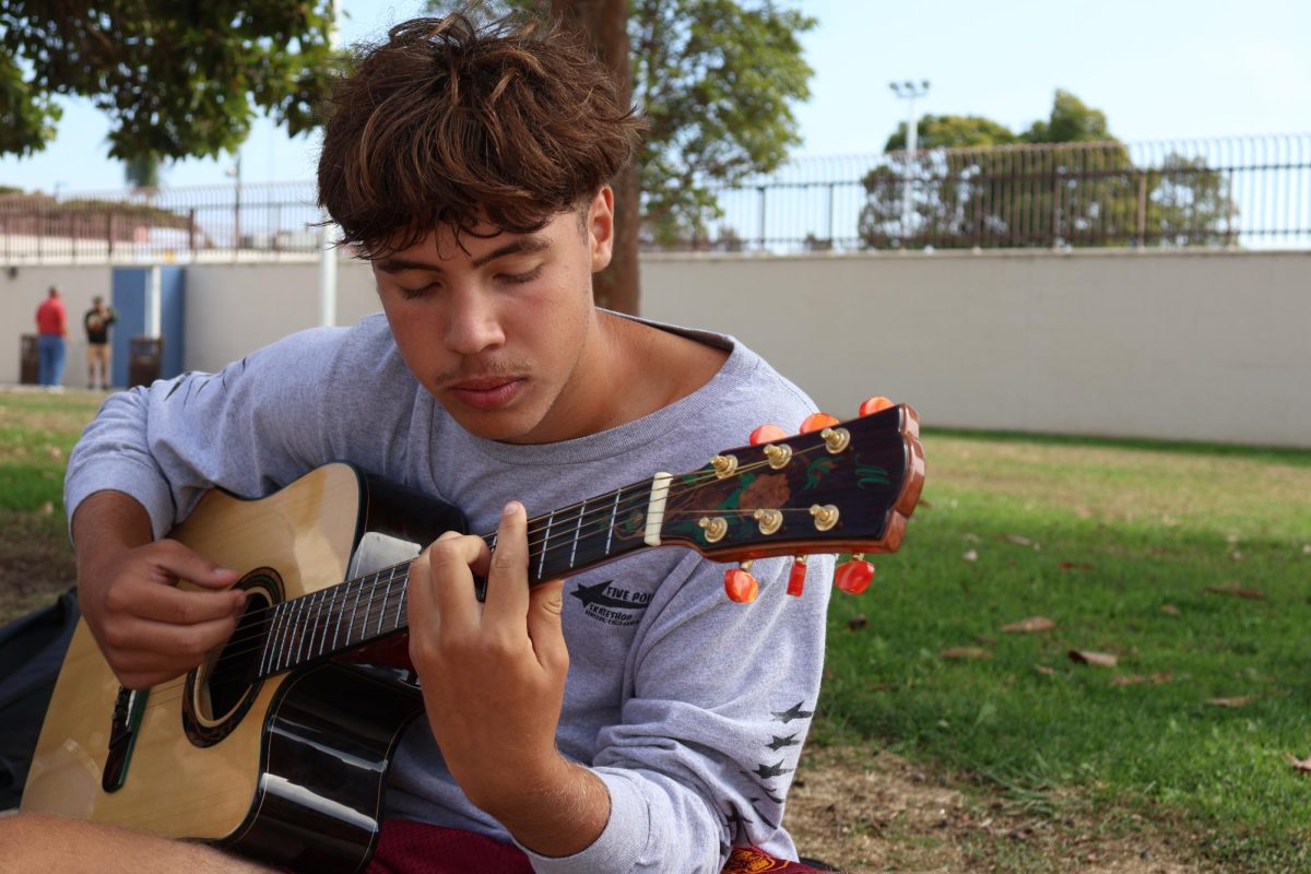 Cru Campbell (9) plays the guitar at the beach courts on Oct. 17
